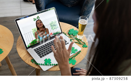 Caucasian woman at bar making st patrick's day video call waving to friend blowing kiss on laptop Caucasian woman at bar making st patrick's day video call waving to friend blowing kiss on laptop 87309258
