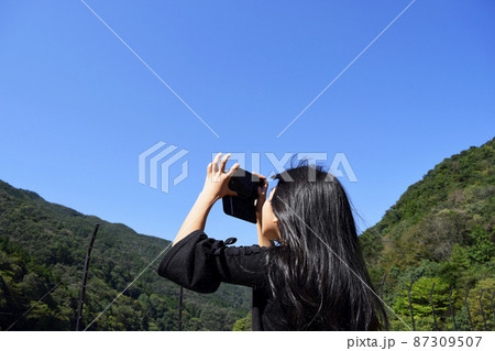 携帯電話で山の写真を撮る女の子 携帯電話で山の写真を撮る女の子 87309507