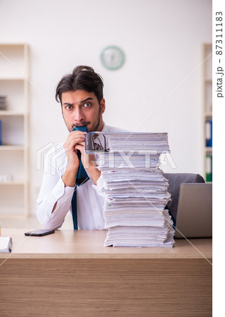 Young businessman employee unhappy with excessive work in the office Young businessman employee unhappy with excessive work in the office 87311183