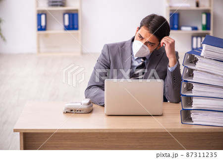 Young male employee working at workplace during pandemic Young male employee working at workplace during pandemic 87311235