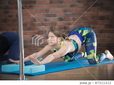 Young pretty woman in colorful blue leggings performing lower back deflection Young pretty woman in colorful blue leggings performing lower back deflection 87311312
