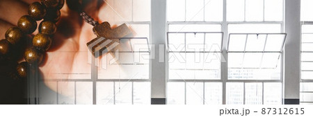Close up view of hand holding a rosary against windows with copy space 87312615