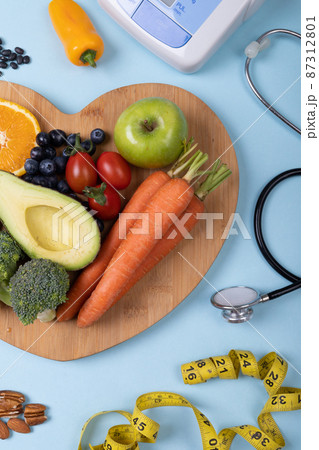 Directly above view of vegetables and fruits on heart shaped board over blue background, copy space Directly above view of vegetables and fruits on heart shaped board over blue background, copy space 87312801