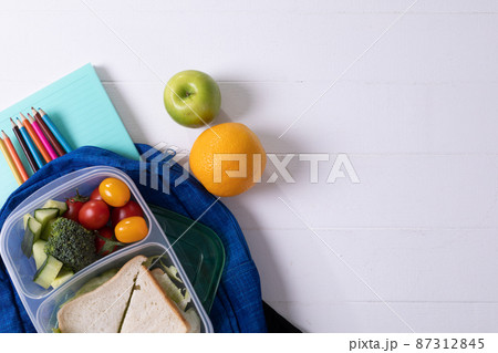 Directly above shot of healthy food and tiffin with school supplies on white background, copy space Directly above shot of healthy food and tiffin with school supplies on white background, copy space 87312845
