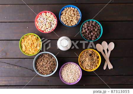 Directly above shot of various breakfast cereals arranged in bowls around milk bottle on table Directly above shot of various breakfast cereals arranged in bowls around milk bottle on table 87313055