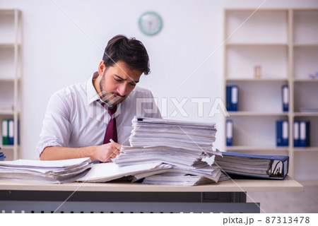 Young businessman employee unhappy with excessive work in the office Young businessman employee unhappy with excessive work in the office 87313478