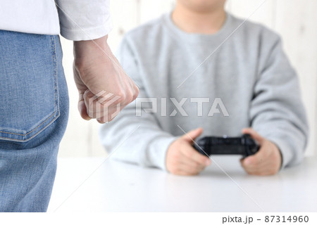ゲームに夢中な子供に怒りを感じる母親の手元 87314960