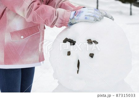 雪ダルマを作る小学生女の子手元 87315033