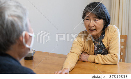 高齢者夫婦の団欒 旦那に手を伸ばし何かを聞き出している高齢者女性 高齢者夫婦の団欒 旦那に手を伸ばし何かを聞き出している高齢者女性 87316353