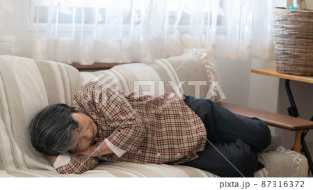 疲れてソファで昼寝をする80代の高齢者女性 疲れてソファで昼寝をする80代の高齢者女性 87316372
