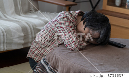 疲れて炬燵でうつ伏せで寝てしまう80代の高齢者女性 疲れて炬燵でうつ伏せで寝てしまう80代の高齢者女性 87316374