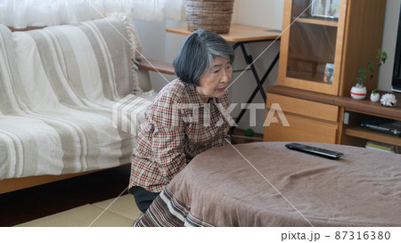 背中を丸めながらこたつに入る80代の高齢者女性 背中を丸めながらこたつに入る80代の高齢者女性 87316380