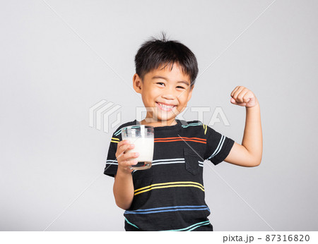 Little cute kid boy 5-6 years old smile holding milk glass and show power strong gesture Little cute kid boy 5-6 years old smile holding milk glass and show power strong gesture 87316820