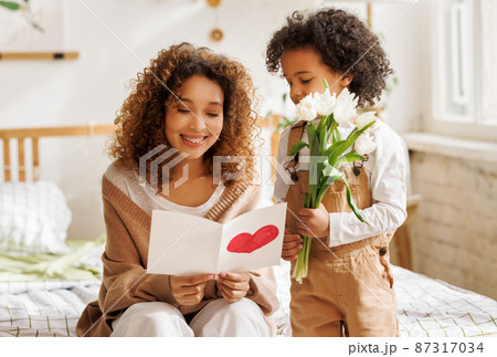 Young ethnic woman getting congratulations from son on Mother's day Young ethnic woman getting congratulations from son on Mother's day 87317034