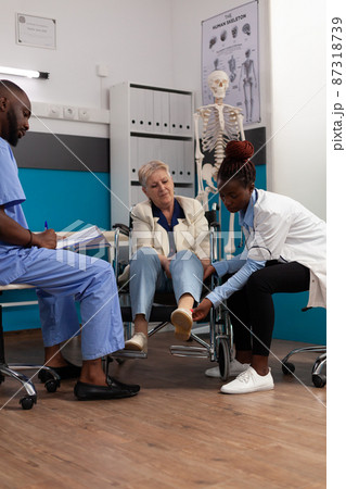 Senior woman patient geeting knee examined during physiotherapy consultation Senior woman patient geeting knee examined during physiotherapy consultation 87318739