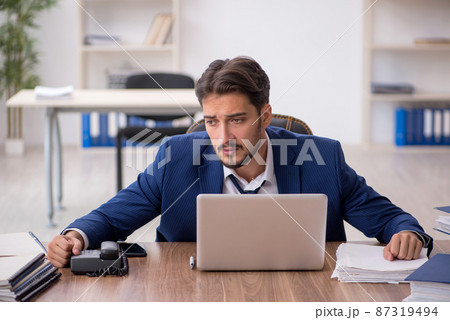 Young male employee unhappy with excessive work in the office Young male employee unhappy with excessive work in the office 87319494