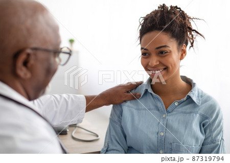 Close up of black male doctor tapping patting patient's shoulder Close up of black male doctor tapping patting patient's shoulder 87319794