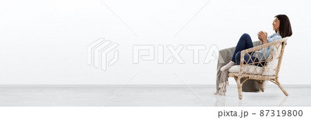 Asian Woman Enjoying Tea In Wicker Chair At Home 87319800