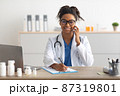 Portrait of smiling doctor looking at camera talking on phone 87319801