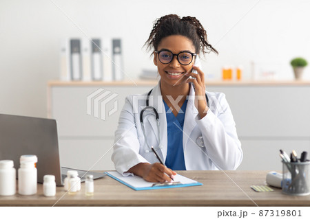 Portrait of smiling doctor looking at camera talking on phone 87319801