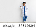 Cheerful female black doctor smiling pointing at copy space 87319804