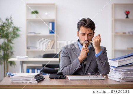 Young male employee unhappy with excessive work in the office Young male employee unhappy with excessive work in the office 87320181