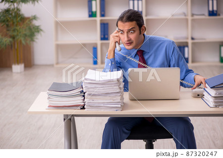 Young male employee unhappy with excessive work 87320247