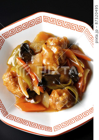 八角形の中華皿に盛り付けられた酢豚を黒背景で俯瞰撮影 87320495