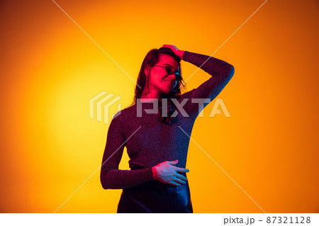 Beautiful young excited girl, student with long dark hair isolated on gradient yellow background in neon light. Concept of emotions, youth 87321128