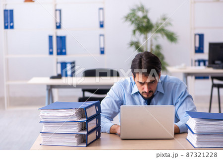 Young male employee and too much work in the office Young male employee and too much work in the office 87321228