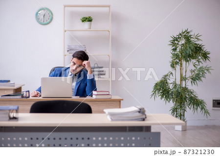 Young male employee being unhappy with excessive work Young male employee being unhappy with excessive work 87321230