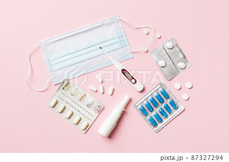 Protective face masks or surgical masks, medicine pills and thermometer on table background. Coronavirus disease. Corona virus concept. Space for text Protective face masks or surgical masks, medicine pills and thermometer on table background. Coronavirus disease. Corona virus concept. Space for text 87327294