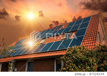 Photo collage of solar panels, photovoltaics on the red roof of a house and a beautiful sky with the setting sun. Alternative electricity source. Concept of sustainable resources Photo collage of solar panels, photovoltaics on the red roof of a house and a beautiful sky with the setting sun. Alternative electricity source. Concept of sustainable resources 87328144