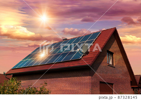 Photo collage of solar panels, photovoltaics on the red roof of a house and a beautiful sky with the setting sun. Alternative electricity source. Concept of sustainable resources 87328145