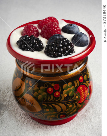 Wooden red patterned cup with berries and yogurt inside 87329440