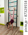 A little girl goes in for sports in her room. 87329558