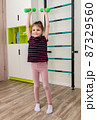 A little girl goes in for sports in her room. 87329560