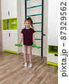 A little girl goes in for sports in her room. 87329562