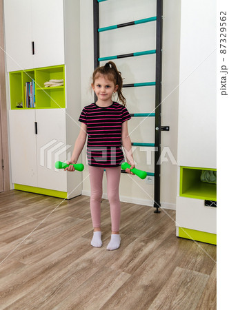 A little girl goes in for sports in her room. 87329562