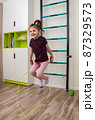 A little girl goes in for sports in her room. 87329573