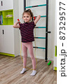 A little girl goes in for sports in her room. 87329577