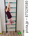 A little girl goes in for sports in her room. 87329580