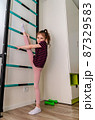 A little girl goes in for sports in her room. 87329583