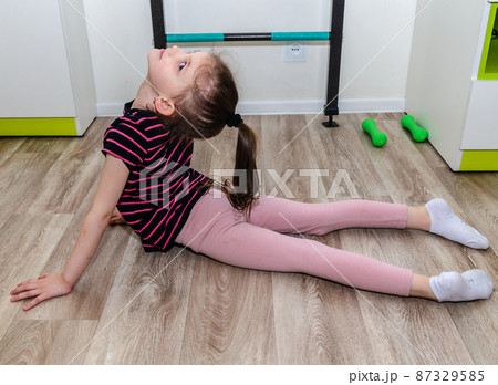 A little girl goes in for sports in her room. A little girl goes in for sports in her room. 87329585