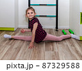 A little girl goes in for sports in her room. 87329588