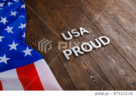 words USA proud laid with silver metal letters on brown wooden surface with flag of United States of America words USA proud laid with silver metal letters on brown wooden surface with flag of United States of America 87331218