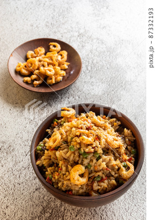 Serving paella with fried shrimp and lemon. Serving food in earthenware. 87332193