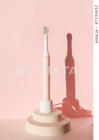 New modern ultrasonic toothbrush. Dental care supplies on cylinder podium on pink pastel background. Oral hygiene, dental and gum health, healthy teeth. Dental products  87334652