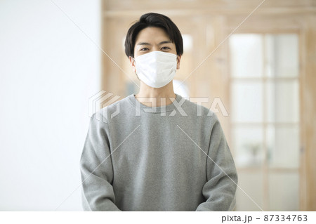 部屋でマスクを付ける30代の男性 部屋でマスクを付ける30代の男性 87334763