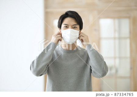部屋でマスクを付ける30代の男性 部屋でマスクを付ける30代の男性 87334765